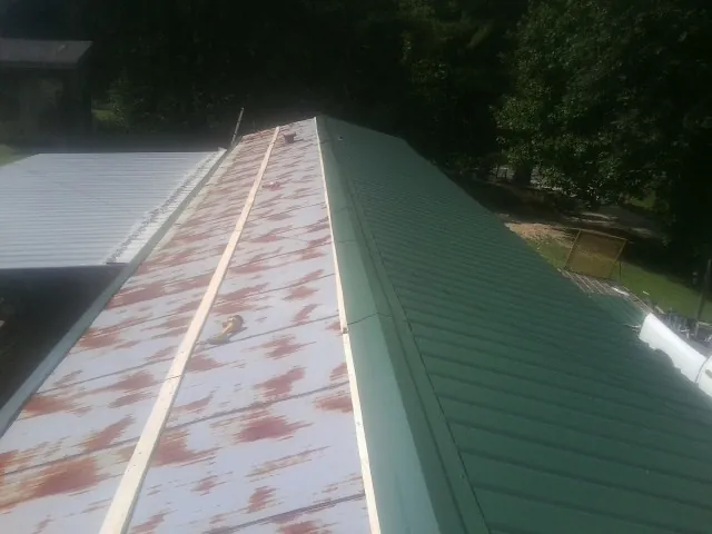 Old rusted panels beside newly installed green metal roofing — Wind Damage Roof Repair by Roofing Brothers in North Collins