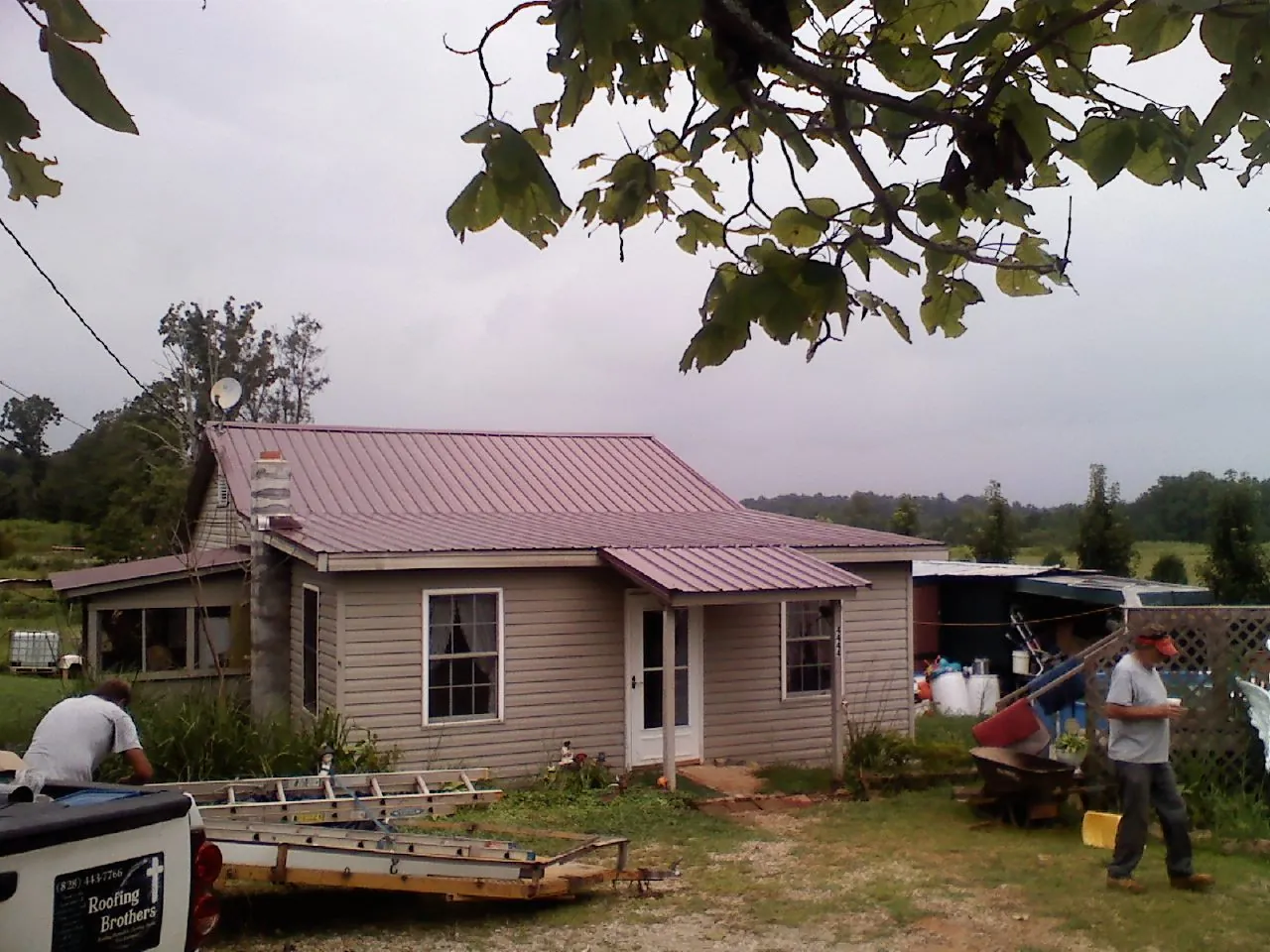 Crew finishing a mauve metal roof on a small farmhouse in North Collins