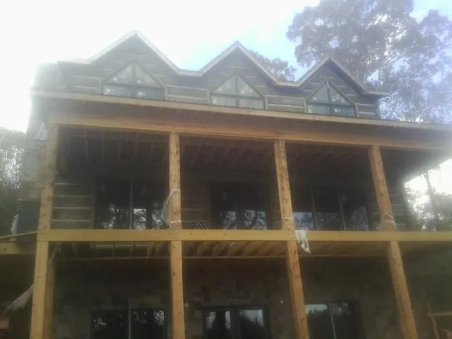 Dormers and porch framing on a large log home under construction — Roof Coating work by our crew in North Collins