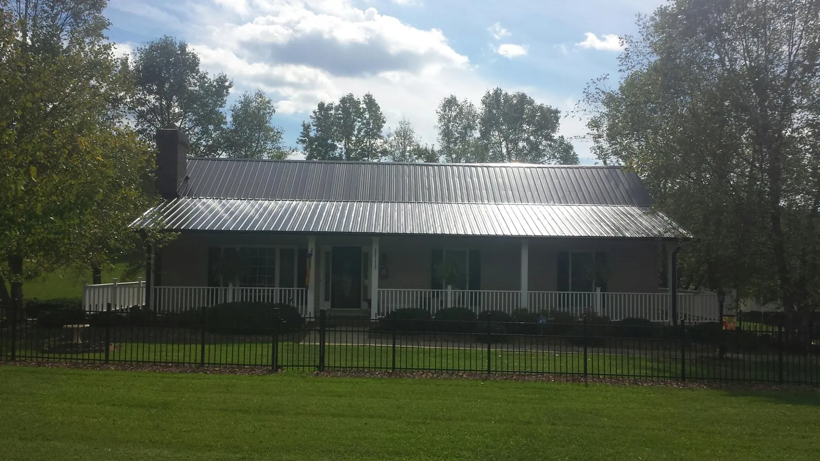 Gray metal roof on a brick ranch with a full width front porch — Gutter Guard Installation work by our crew in North Collins