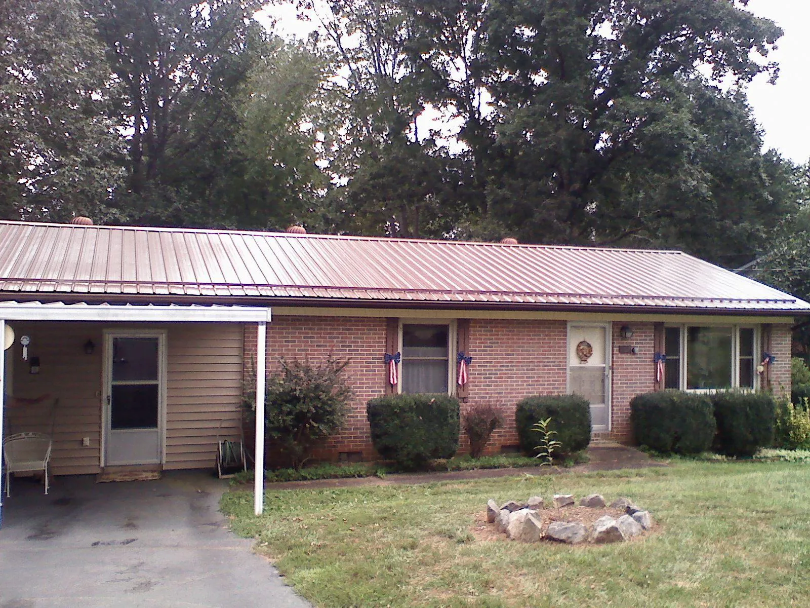 Bronze metal roof and carport on a brick ranch home — Roof Repair work by our crew in North Collins