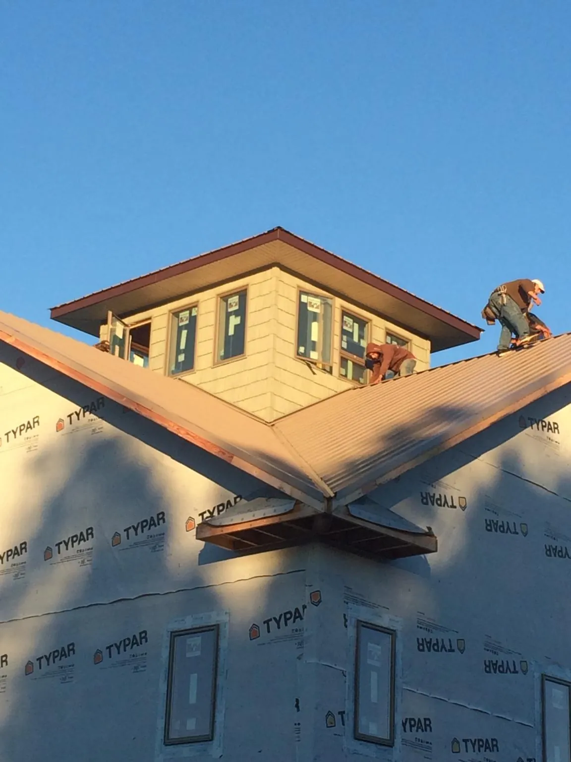 Roofers working around a rooftop cupola on a new metal roof at sunset — Roof Waterproofing in North Collins by Roofing Brothers